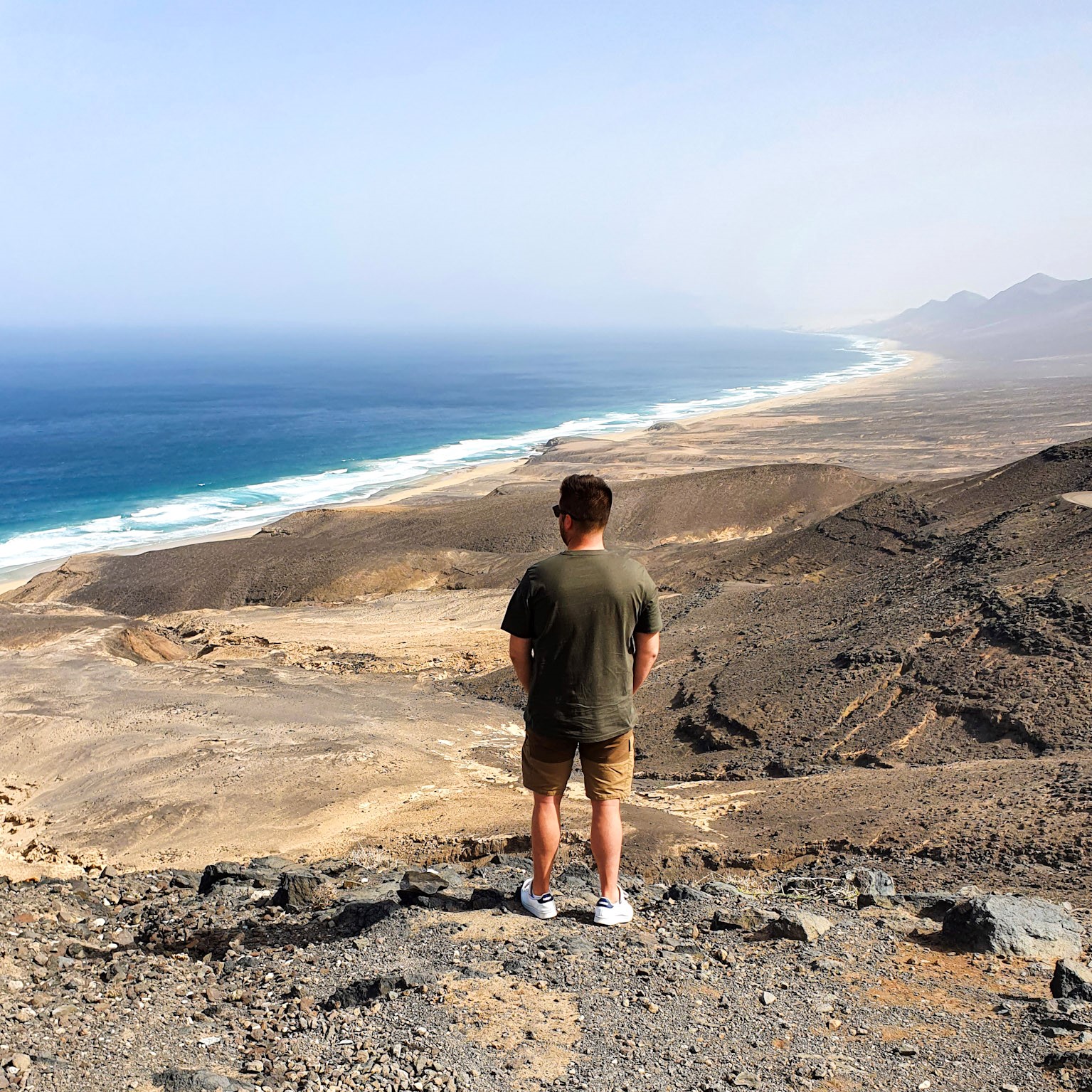 homme-debout-face-a-une-plage-depuis-un-point-de-vue