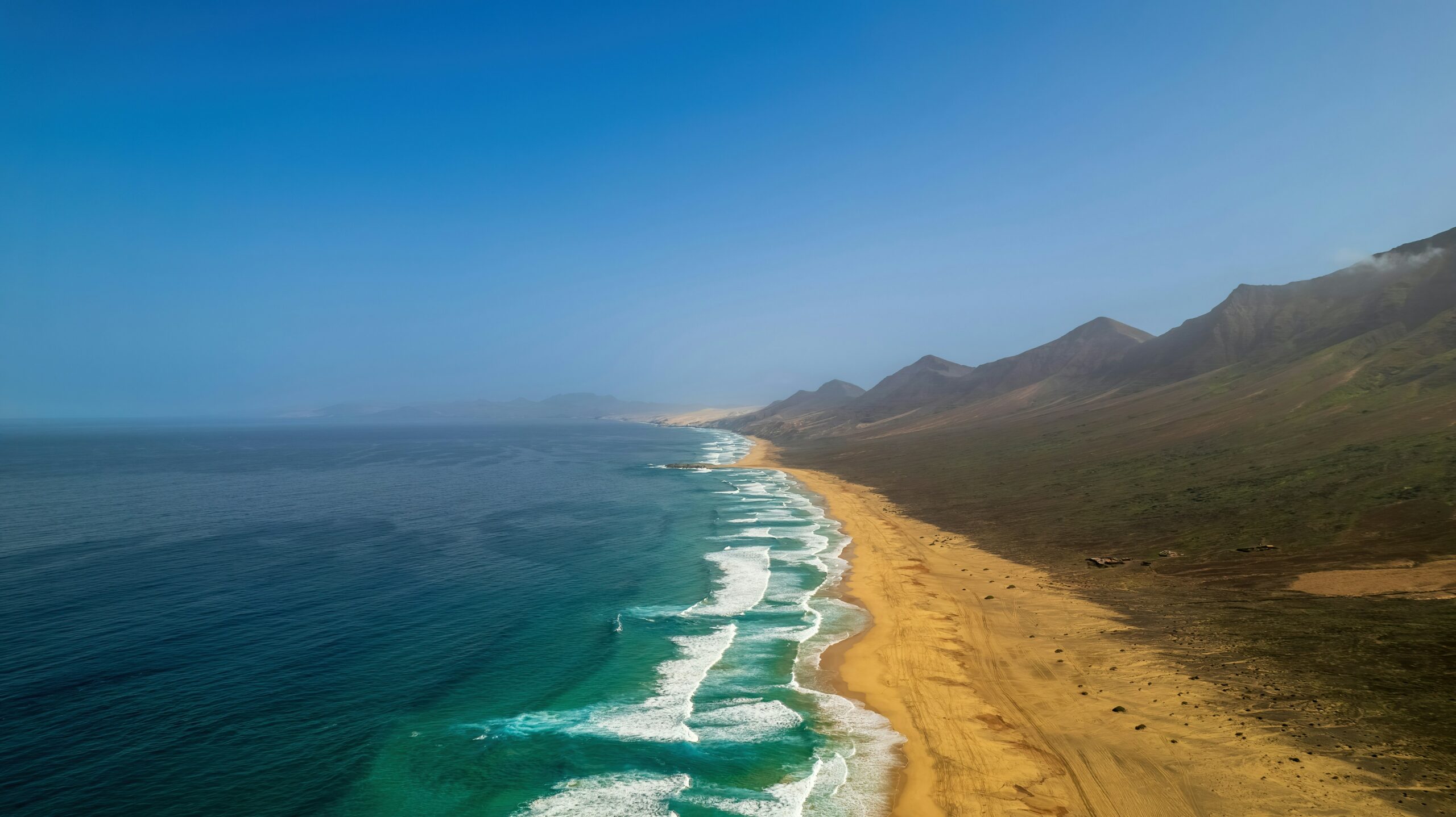 quelle-ile-des-canaries-choisir-fuerteventura-une-plage-avec-un-plan-deau-et-des-collines-en-arriere-plan