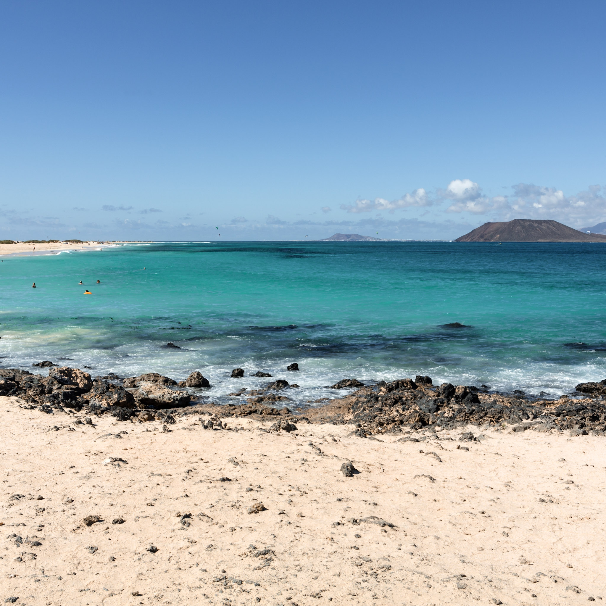 plage-de-sable-bordee-deau-turquoise-avec-un-volcan-en-arriere-plan